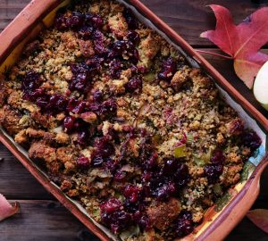 apple and raspberry crumble surrounded by maple leafs on rustic table
