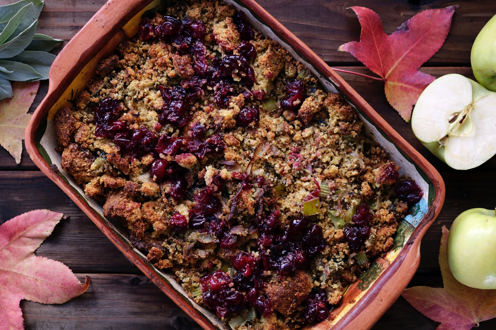 apple and raspberry crumble surrounded by maple leafs on rustic table