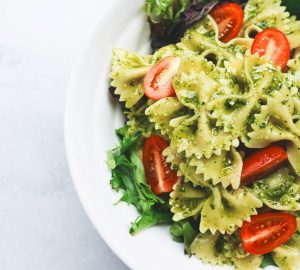 close up of bowtie pesto pasta with cherry tomatoes and arugula