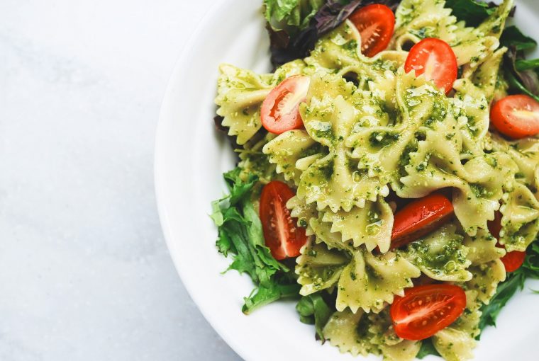close up of bowtie pesto pasta with cherry tomatoes and arugula