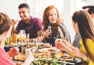 group of friends sitting at table eating vegan food
