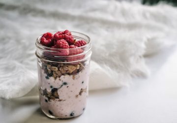 close up of overnight oats with raspberries in mason jar