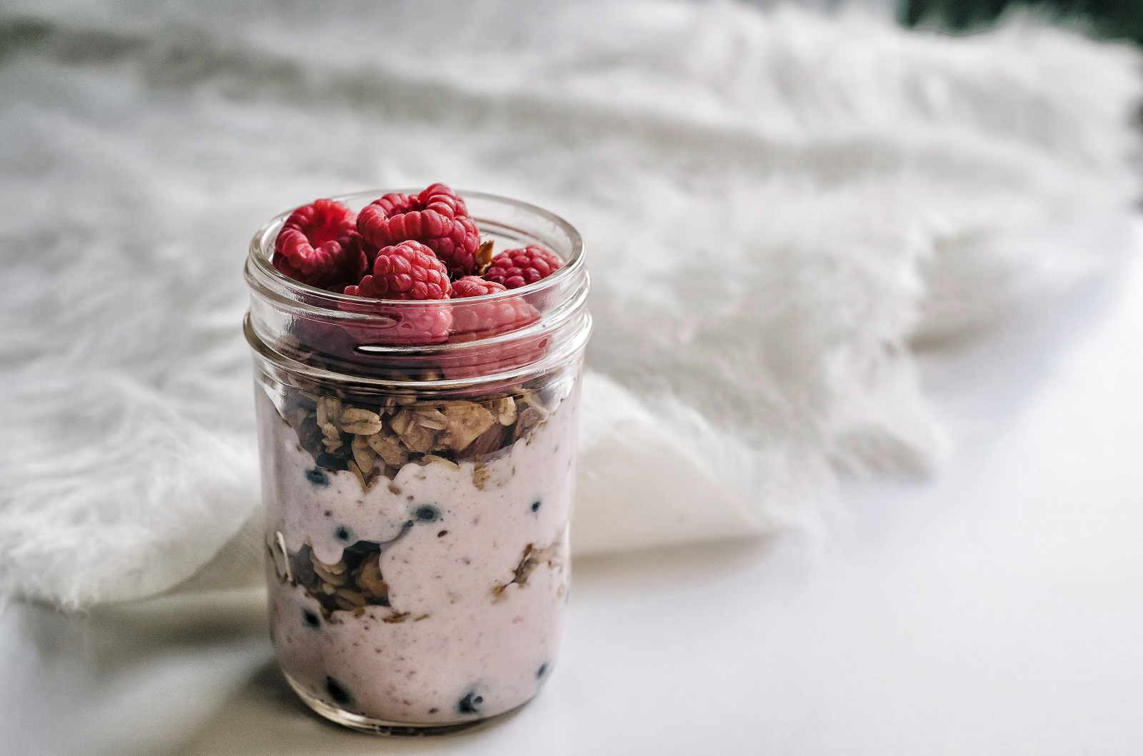 close up of overnight oats with raspberries in mason jar