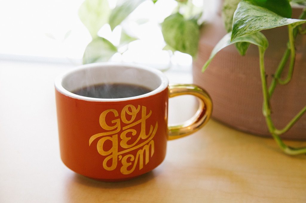 orange cup of coffee with 'Go get 'em" written on cup