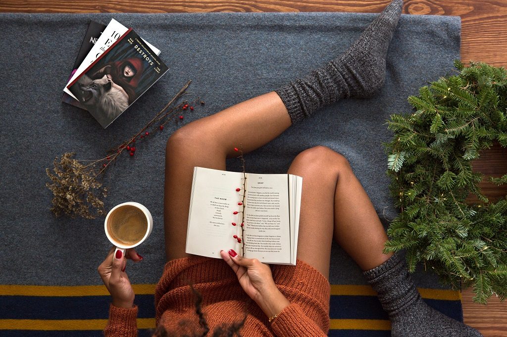 woman drinking tea and reading book wearing cozy socks