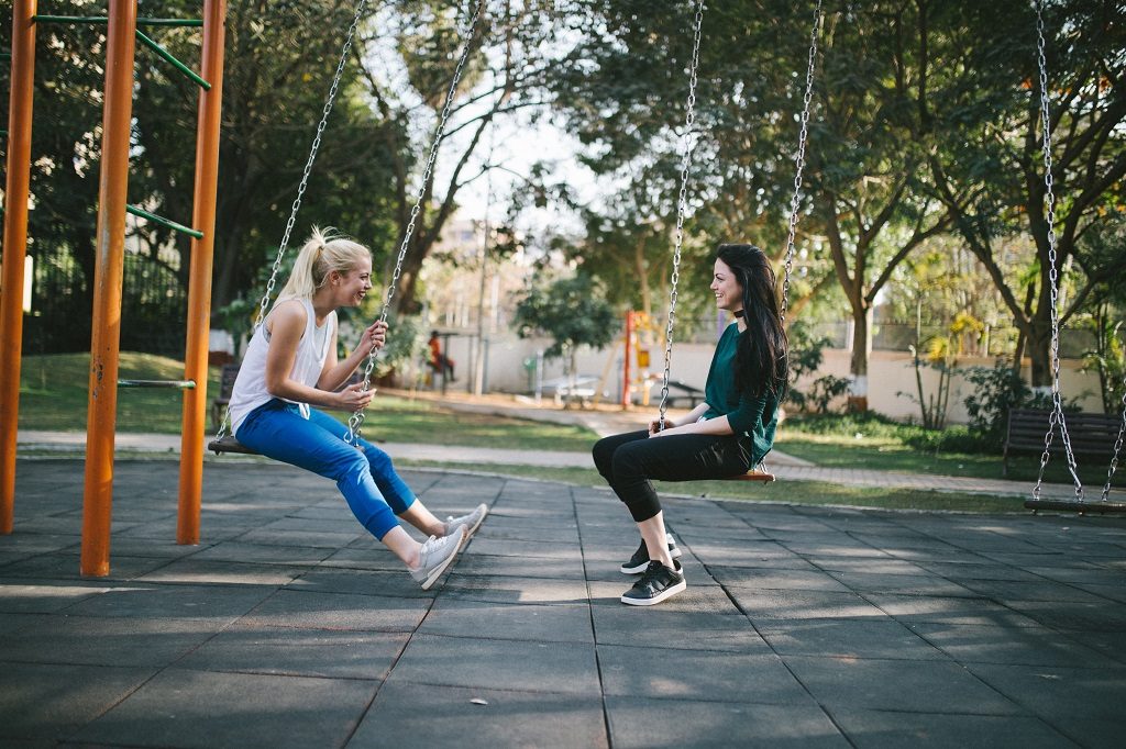 two young women on swing set at the park
