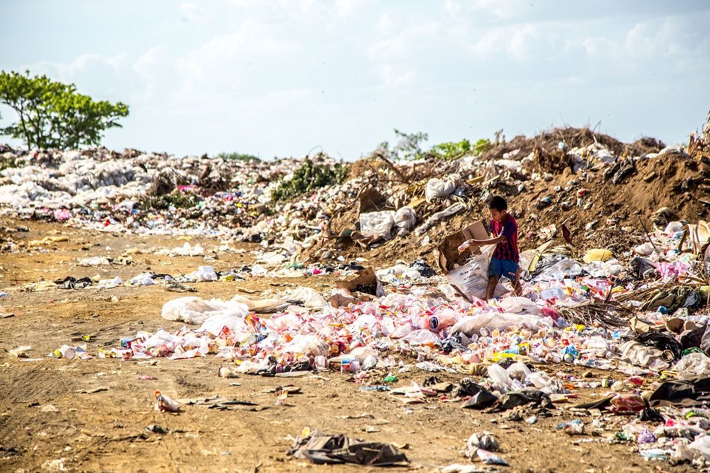 young boy walking on piles of trash