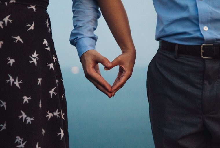 woman and man making heart shape with joined hands