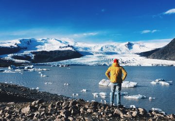 man standing in front of melting glacier
