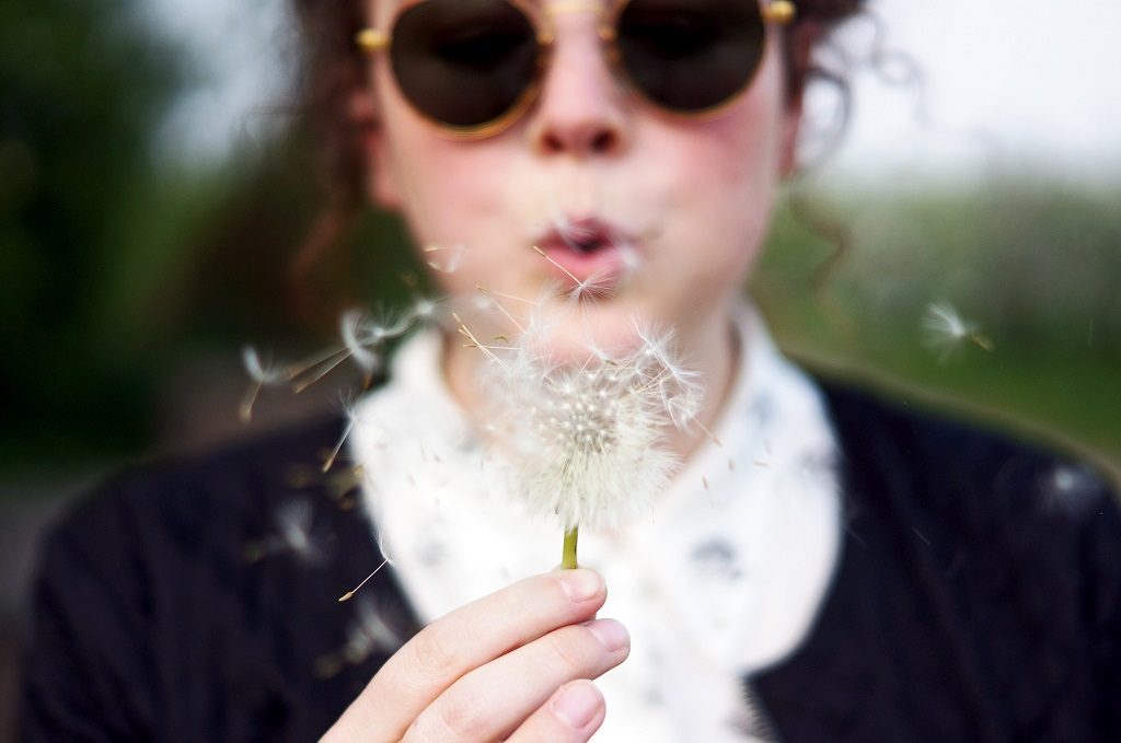 woman blowing on dandelion